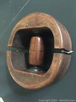 Top view of the antique wooden hat stretcher showing the semicircular shape and central spindle with metal fittings.