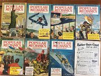 Photo showing all 8 Popular Mechanics magazines from the 1950s with visible covers, including Golden Anniversary Issue and various colorful illustrated covers depicting mid-century technology and scenes.