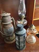 Four vintage oil lamps and lanterns shown together on wooden surface