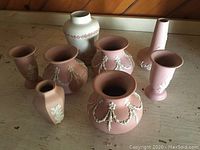 Nine pieces of vintage ECanada art pottery on wooden surface showing their shapes and decoration.