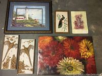 Photo showing six art pieces including a framed lighthouse painting, two vertical bird prints, a muted figure painting, and two floral paintings