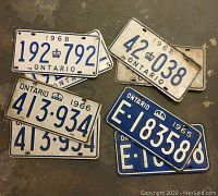 Four vintage Ontario license plates from the 1960s displayed on a floor.