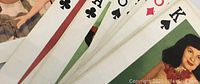 Close-up of playing cards showing pin up girl illustrations and card faces with suits and ranks.