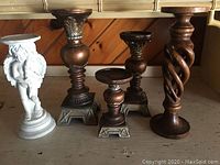Lot of five decorative candle holders arranged side by side on a wooden surface, showing full shapes and bases.