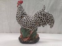 Front side of ceramic rooster figurine showing polka dot patterns and detailed base.
