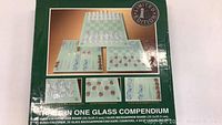 Photo of the box front showing the title 'Three In One Glass Compendium' and images of the glass chess/checkers board and backgammon board with pieces and counters.