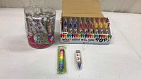 Photo of POP Point Crayons in retail packaging including a clear plastic container, and a retail display box with multiple crayons.