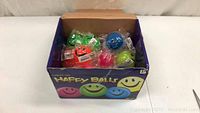 Box of 22 Happy Balls, individually wrapped, visible in various colors with smiley face design.