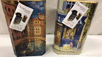 Two decorative wine boxes shown upright side by side featuring European canal and street scenes, each with Heritage tags.