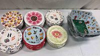 Overview of various stacks of paper plates and bowls showing different colorful patterns including donuts, flowers, shoes, food items, and utensils.