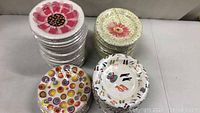 Four stacks of paper plates showing different colorful designs and unopened plastic wrapping