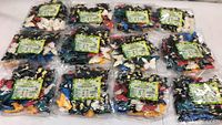 12 sealed clear bags each containing multiple colorful plastic butterfly toys spread out on a surface.