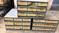 Three metal parts bins stacked, showing multiple labeled drawers containing various specialty screws.