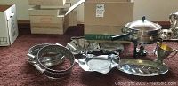 Photo of all items in the lot laid out on carpet, showing serving platters, fondue set with burner, and small pitcher