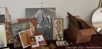 Collection of framed pictures and artwork including large mountain photograph, religious imagery, and hand-painted plaques