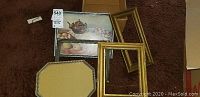 Photo showing assorted frames and one framed picture arranged on carpet