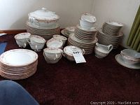 Full lot of Czechoslovakia porcelain dinnerware displayed on carpet with plates, bowls, cups, and serving pieces grouped.