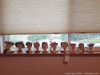 Group shot of ten lady head vases on windowsill
