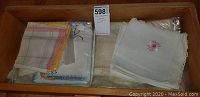 Photo of the vintage linens spread in wooden drawer showing assortment of handkerchiefs and cloths with lace and embroidery details.