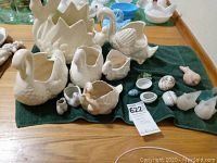 Overview of seven ceramic swans, three glass birds, and four glass eggs arranged on a green cloth