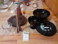 View of all glassware items including black and purple decorative plates, bowls, candy dish, glasses, and vases arranged on floor.