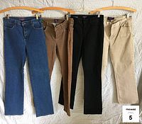 Four pairs of jeans hanging on wooden hangers, showing front view. Colors are blue, medium brown, black, and tan.