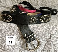Four belts laid out, showing wide black studded belt in front and three slimmer belts behind (black leather-like, pink leather-like, blue vinyl patent).