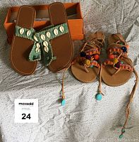 Pair of sandals showing the Mia lace-up leather sandals with colorful trims and KK White Mountain fabric sandals with shell trims on top of a light fabric background with shoe box and lot identifier visible.