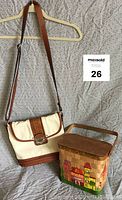 Two vintage bags displayed: leather white and brown shoulder bag on hanger and woven basket handbag on surface
