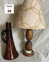 Both lamps displayed with visible power cords. The blown glass lamp has a tapered shape with mottled amber and brown colors. The nautical table lamp has a wool shade with rope pattern and wooden rounded base.