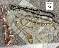 Overview of 5 necklaces and embroidered fingertip towel laid flat on fabric