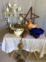 Full view of the lot on a table showing shovels, net floats, ceramic pieces, metal shelf, and wooden star.