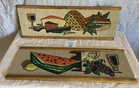 Two vintage aquarium gravel art panels arranged on fabric, showing detailed colorful fruit and cheese scenes