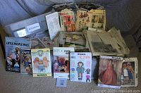Full lot of vintage doll, doll clothes, stuffed toy, and costume sewing patterns laid out on floor showing brands and variety.