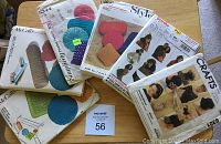 Photo of six vintage sewing patterns including 4 smocked pillow patterns and 2 women's accessory patterns with vintage packaging and illustrations from the 1960s.