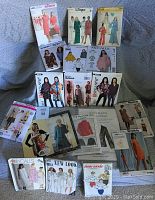 Photo of multiple vintage sewing patterns arranged on a couch showing covers with drawings and photos of 1970s-1980s women's fashion garments.