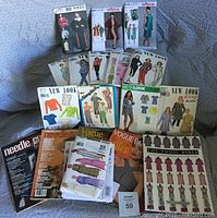 Photo showing multiple vintage and classic paper sewing patterns and craft magazines arranged on fabric surface