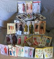 Front view of numerous vintage and classic sewing pattern envelopes in a spread, showing women's fashion designs from the 1960s and 1970s, including dresses, skirts, and tops.