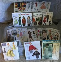 Photo showing a wide selection of sewing patterns spread out, featuring vintage and newer designs, some sealed and some opened.