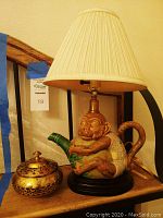 Monkey teapot lamp with cream pleated lampshade and decorative gold metal bowl with lid.