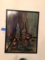 Full view of framed acrylic still life painting with bottles, bowl, and fruit on a textured background.