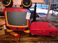 Front view of Disney Mickey Mouse CRT TV and DVD player with remote on wood table
