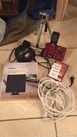 Photo showing full lot with VTech cordless phone base, silver tripod, black alarm clock, whistle key finder in box, white extension cord, Liger TV antenna box