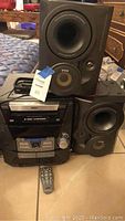 Overall view of RCA stereo main unit, two detachable speakers, and remote on floor
