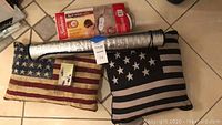 Photo showing two American flag themed throw pillows, lavender soap, heating pad with remote controls, and rolled reflective car window shield
