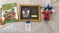 Full display of all items in the lot: framed Goofy Movie film cell, Mickey Mouse glow spinner figure, and two Sesame Street Golden Books.