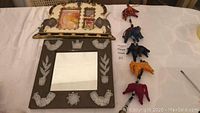Aztec style mirror, elephant photo frame, and string of elephant hanging decorations on table.