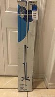 Full view of the boxed Home Patio outdoor spa shower standing upright against a door.