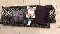 King size animal print comforter, two purple throw blankets, and floral phrase canvas on tiled floor
