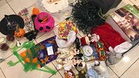 Various Halloween and Christmas decorations spread on the floor including pumpkin buckets, spider web, plush toys, and trays.